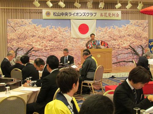 建装桜の前であいさつする山本会長